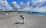 Gunhild samler muslingskaller på stranden med byen Torreguadiaro i baggrunden. Gunhild samler muslingskaller på stranden med byen Torreguadiaro i baggrunden.