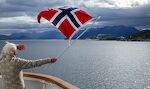 En passager vinker med flaget til nogle venner, som er camperet på øen Åmnøya nær Ørnes. En passager vinker med flaget til nogle venner, som er camperet på øen Åmnøya nær Ørnes.