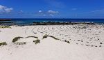 Nogen har moret sig med at lave en spiral af sorte lavasten i det hvide sand.